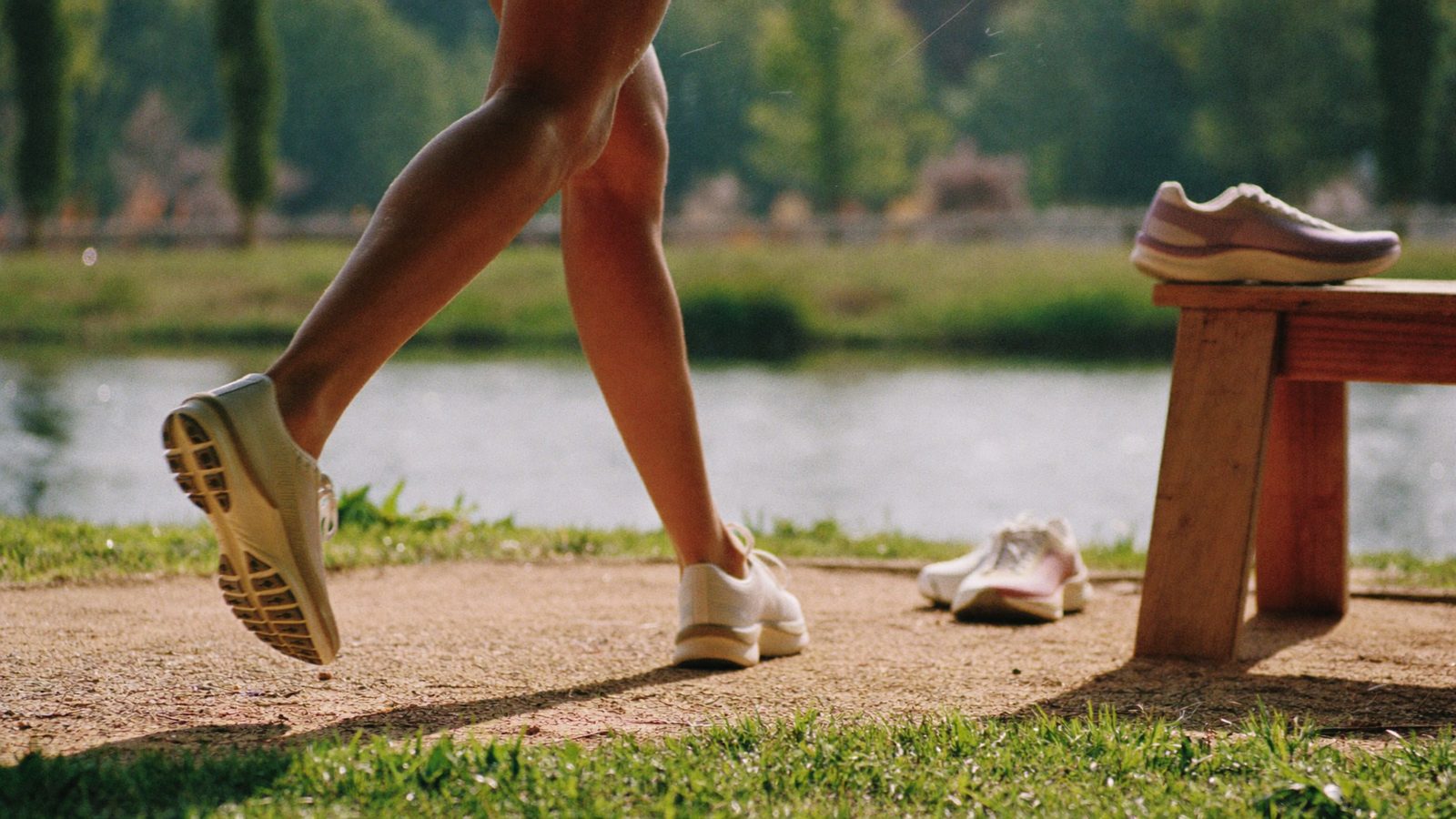 Pies de una corredora con zapatillas de running en un camino junto al río