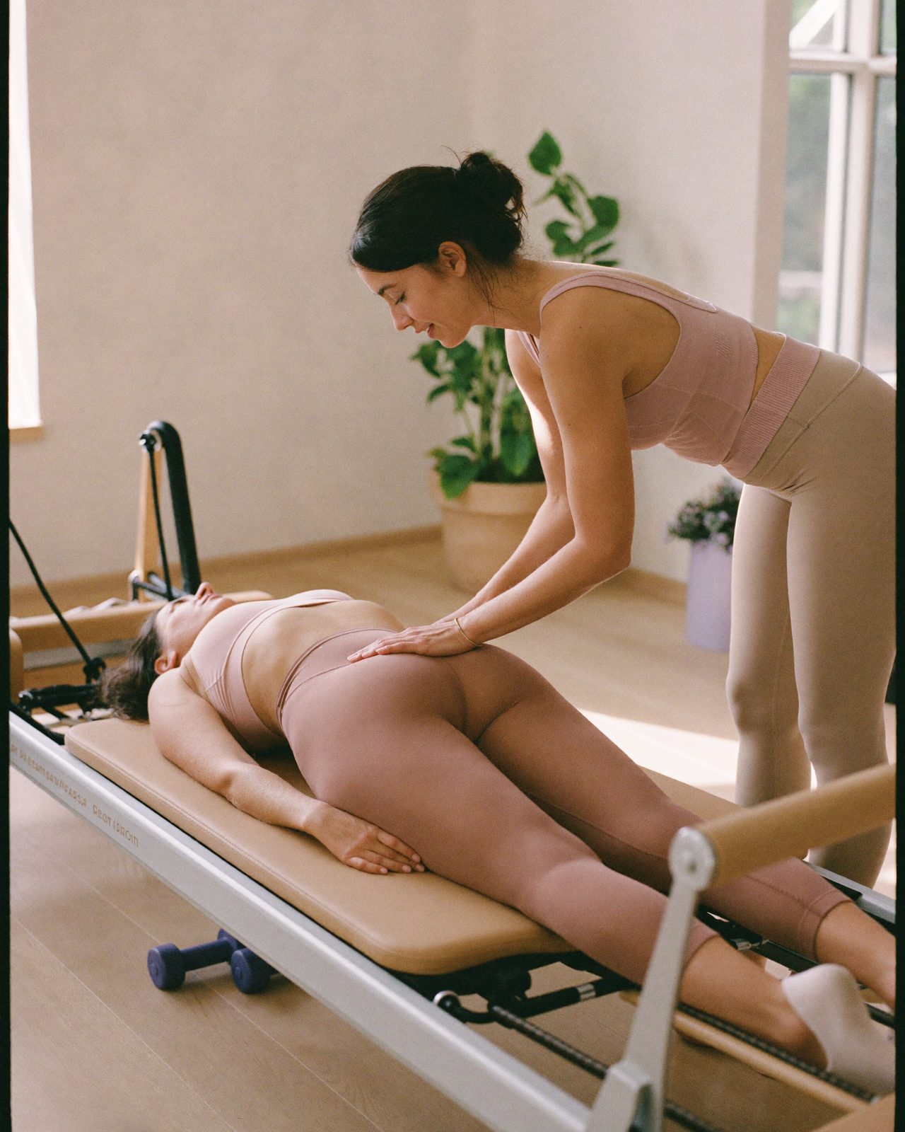 Instructora corrigiendo la postura de una alumna en una sesión privada de reformer