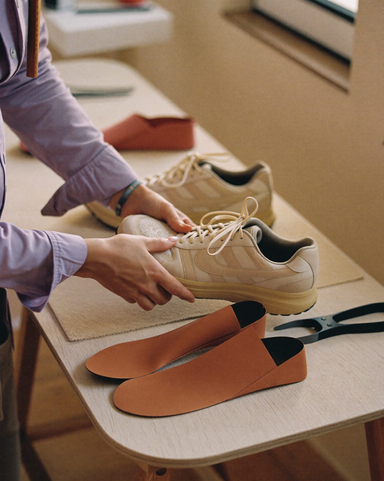 Podóloga mostrando un par de plantillas personalizadas junto a una zapatilla